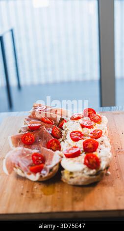Italienisches Baguette mit cremiger Burrata, Schinken, Kirschtomaten, Olivenöl und Kräutern. Ein einfaches, elegantes, italienisch inspiriertes Mittagessen oder Vorspeise, frisch Stockfoto