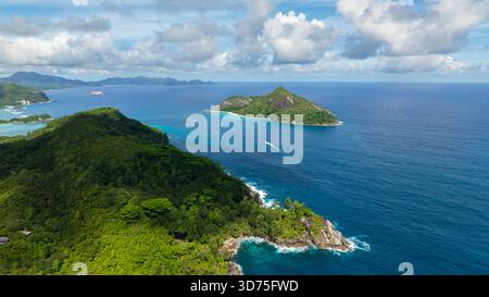Weitläufiger Blick auf das Meer mit zwei Inseln, umgeben von klarem blauem Wasser und Wolken. Seychellen, Mahe. Stockfoto