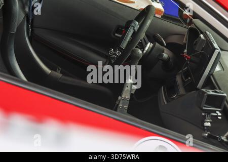 Nahaufnahme des Innenraums eines modernen roten Sportwagens mit elegantem schwarzem Ledersitz, Lenkrad und Armaturenbrett. Das Cockpit-Design erzeugt ein kraftvolles Gefühl von Stockfoto