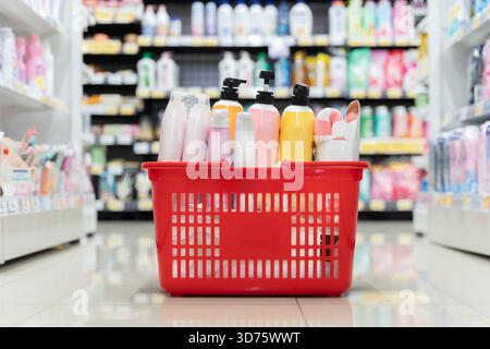 Roter Warenkorb gefüllt mit Körperpflege- und Haushaltsprodukten in einem Supermarkt, ideal für Themen wie Verbraucherverhalten, Einzelhandel Stockfoto
