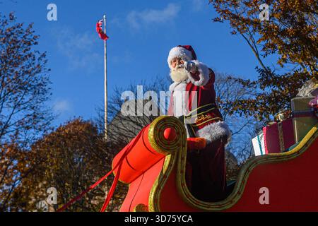 TORONTO, ONTARIO, KANADA - 23. NOVEMBER 2025: Der Weihnachtsmann winkt der Menge, während er in seinem legendären rot-goldenen Schlitten fährt, der mit einem g-gewickelten Haufen hoch gestapelt ist Stockfoto