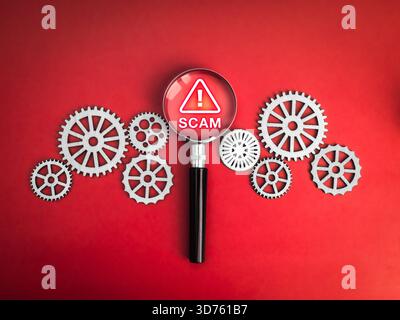 Betrugswarnkonzept mit Vergrößerungsglas, das Warnzeichen zwischen mechanischen Getrieben auf Rot markiert, das Betrugserkennung und Verhinderung von Cyberbedrohungen symbolisiert Stockfoto