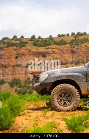 Talas, Kasachstan - 13. Mai 2024: Nahaufnahme des Vorderviertels eines matschigen Toyota Land Cruiser 100 mit einem speziellen Stoßfänger, der gegen ein verschwommenes rotes R gesetzt ist Stockfoto