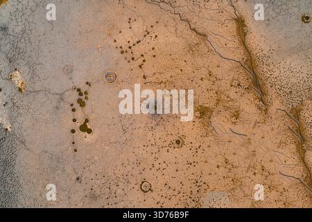 Abstrakter Luftdrohenshot von dehydrierter Bodenoberfläche mit tiefen Rissen und kleinen getrockneten Pfützen. Konzept von schwerer Dürre, Wasserknappheit, globaler Erwärmung und Auswirkungen des Klimawandels auf die Natur. Stockfoto