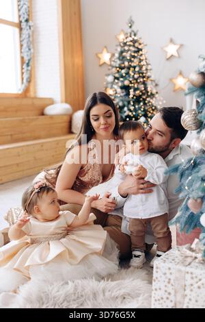 Eine Familie genießt während der Feiertage eine schöne Zeit zusammen in einem gemütlich dekorierten Wohnzimmer, umgeben von einem Weihnachtsbaum und festlichen Ornamenten Stockfoto