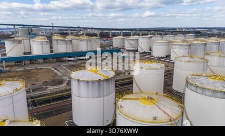 Aus der Vogelperspektive einer weitläufigen Industrielandschaft, die von Reihen zylindrischer Lagertanks mit weißen Wänden und gelben Spitzen dominiert wird, ein Beweis für Indexierung Stockfoto