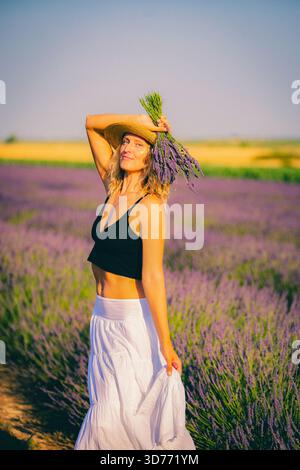 Eine junge Frau mit einem Lavendelstrauß in einem Strohhut Stockfoto