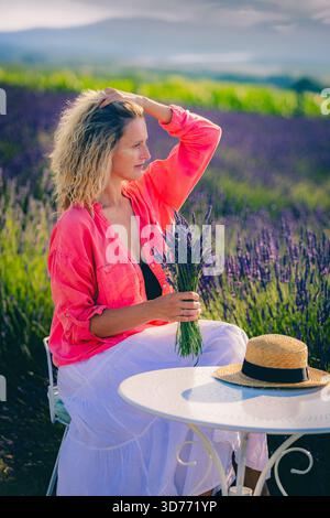 Eine junge Frau mit einem Lavendelstrauß auf einem Lavendelfeld Stockfoto