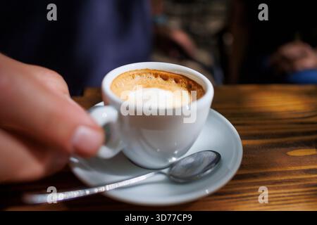 Eine Tasse Kaffee aus der Nähe, die auf einem Holztisch serviert wird Stockfoto