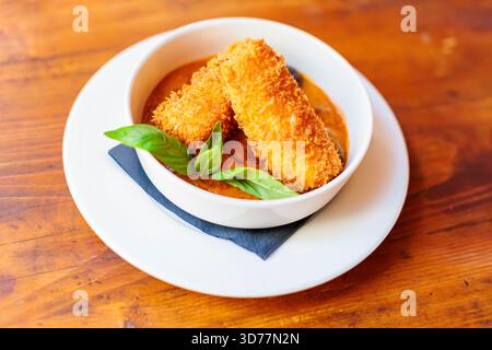 Knusprig gebratene goldene Kroketten mit Sauce auf einem weißen Teller Stockfoto
