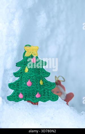 Vertikales Bild Gestrickter Weihnachtsbaum im Gletscherschnee mit verschwommenem Weihnachtsmann. Viel Platz zum Kopieren von Text auf dem mobilen Hintergrund. Stockfoto