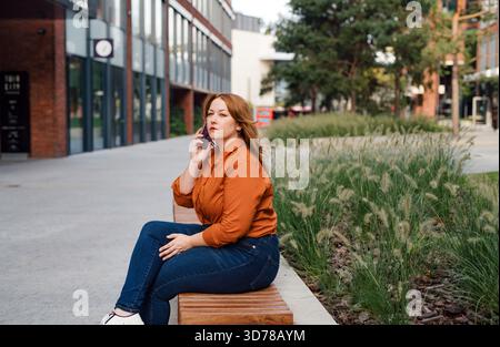Kurvige Erwachsene Frau, die draußen telefoniert. Stockfoto