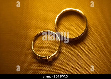 Schließen Sie zwei goldene Hochzeitsringe auf strukturiertem Stoffhintergrund Stockfoto