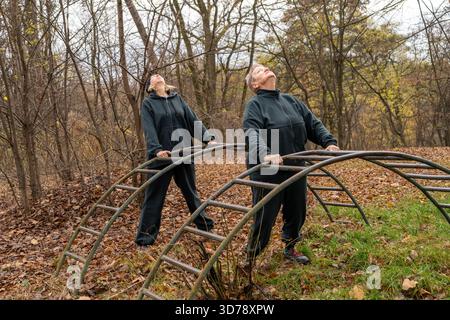 Zwei Frauen dehnen Sport im Park. Training für ältere Frauen mit Trainer Stockfoto