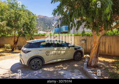 Nahaufnahme des Akti Hotels Elektroautos, das auf dem Parkplatz geparkt ist und an einer stationären Station im Hintergrund aufgeladen wird. Kos. Griechenland. Stockfoto