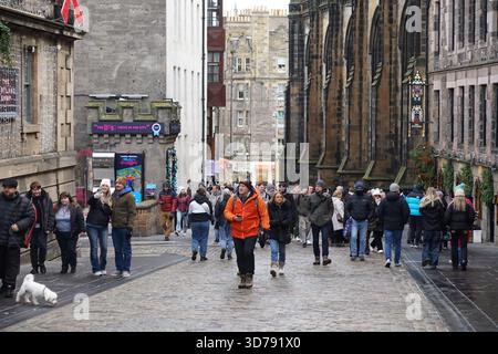 Geschäftige Straßenszene in Edinburghs Altstadt, mit Fußgängern, die entlang einer Kopfsteinpflasterstraße zwischen historischen Gebäuden spazieren. Edinburgh, Schottland Stockfoto