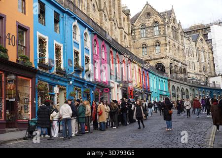 Menschenmassen laufen entlang der Victoria Street in Edinburgh, gesäumt von farbenfrohen historischen Geschäften und Kopfsteinpflasterpflaster.Edinburgh, Schottland Stockfoto