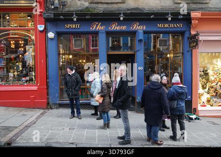 Leute stehen vor der Bow Bar an der Victoria Street in Edinburgh, umgeben von farbenfrohen historischen Geschäften. Edinburgh, Schottland Stockfoto