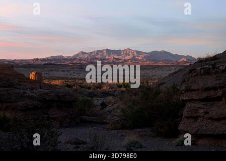 Dieses Bild wurde in der Lake Mead National Recreation Area in Nevada aufgenommen. Es bietet Berge in der Ferne, beleuchtet durch das warme Licht des Sonnenuntergangs. Stockfoto