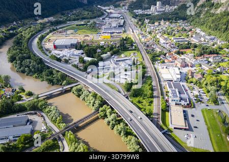 Aus der Vogelperspektive auf den braunen Fluss, der sich durch die Landschaft schlängelt, Brücken über das Wasser und die Autobahn, die durch die Stadt führt, Peggau, Stall Stockfoto