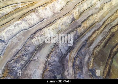 Aus der Vogelperspektive der rauen, terrassenförmig angelegten Landschaft, wo Erdtöne in einem dramatischen Zusammenspiel von Licht und Schatten auf den Himmel treffen, Eisenerz, Steiermark, Österreich. Stockfoto