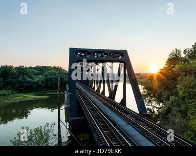 Dies ist ein Blick bei Sonnenuntergang auf die Lawrenceburg Bridge, ein durchgehendes Fachwerk, das eine Eisenbahn über den Great Miami River zwischen Indiana und Ohio führt. Stockfoto