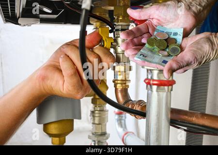 Hände, die ein Kesselventil einstellen, während eine andere Hand Euro-Geld hält. Stockfoto