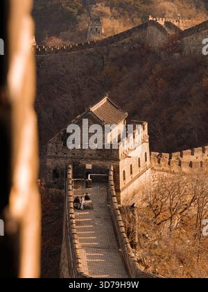 Blick auf die alte Chinesische Mauer, einen Steindrachen, der sich unter warmem Licht über das zerklüftete Gelände schlängelt, ein Zeugnis der Geschichte, Peking Stockfoto