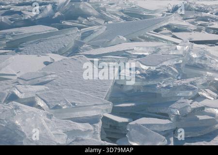 Die Ansammlung großer, transparenter und schneebedeckter Eisblöcke im Winter ist wahrscheinlich auf einem gefrorenen See oder Meer. Das Eis ist in viele scharfe Teile gebrochen Stockfoto