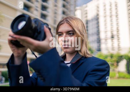 Junge Fotografin mit Kamera nimmt Fotos in der städtischen Umgebung auf Stockfoto