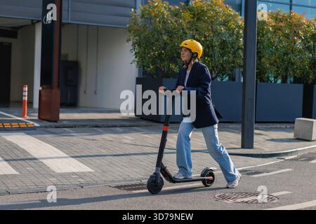 Eine junge Frau fährt mit Helm auf der Straße mit Elektromobil Stockfoto