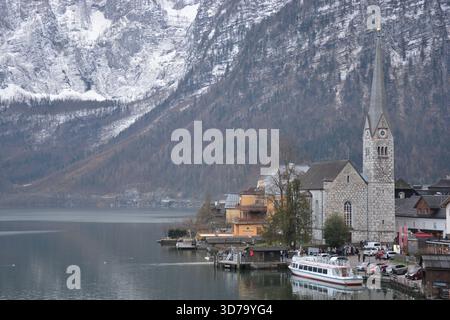 Das Bild zeigt einen klassischen Blick auf Hallstatt, Österreich, mit einer kleinen Kirche am See mit einem hohen Spitzturm. Stockfoto