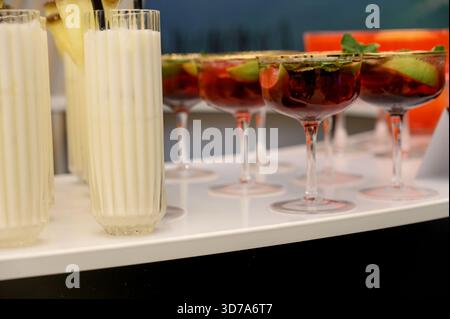 Pina Colada Cocktails und rote alkoholische Getränke an der Bar. Helle und dunkle Cocktails mit Ananas, Limette und Pfefferminze auf einer Party. Stockfoto