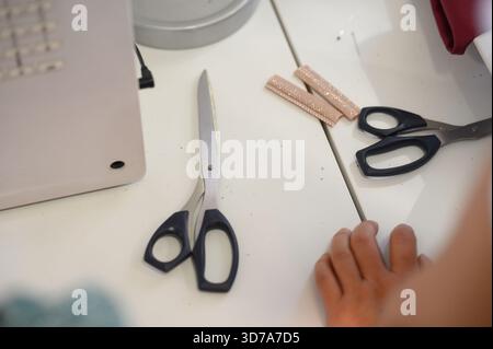 Nahaufnahme einer Werkbank mit Schneiderschere und Nähband. Nahaufnahme eines Arbeitsplatzes einer Schneiderin oder einer Nadelfrau mit Schere Stockfoto