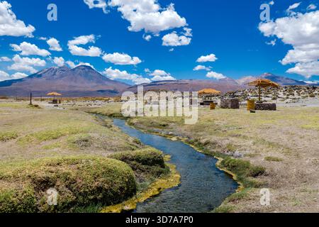 Ein Blick auf einfache touristische Infrastruktur und einen fließenden Bach in der trockenen Landschaft bei Caspana in der Atacamawüste von Chile. Stockfoto