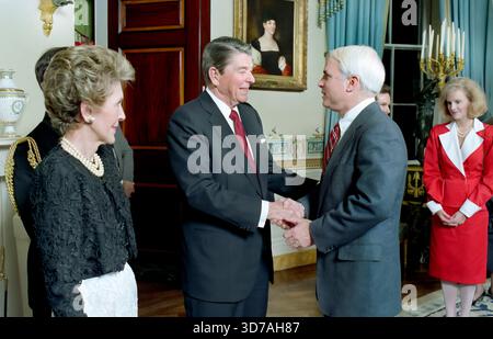 US-Präsident Ronald Reagan und US First Lady Nancy Reagan begrüßen John McCain im Blue Room des Weißen Hauses während eines Abendessens für neu gewählte Mitglieder des 100. Kongresses, Washington, D.C., USA, Präsident Ronald Reagan White House Photographic Office, 3. März 1987 Stockfoto