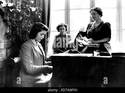 Entspannung Von Ihren Mühsamen Kriegsaufgaben Suchen. Prinzessin Elizabeth am Klavier unterhält ihre Mutter und ihre jüngere Schwester. Ihre Majestäten, der König und die Königin, und ihre Kinder zu Hause 'irgendwo auf dem Land', zeigen ihre große interessierte Musik. Die beiden Prinzessinnen, Prinzessin Elizabeth und Prinzessin Margaret Rose, sind wie ihre Mutter beide eine versierte Pianisten. 1. Januar 1943. (Foto von Fox Photos). Stockfoto