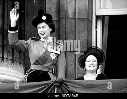 Königin im Palast nach dem Trooping -- die Königin, die die Uniform des Obersten Obersten der Scots Guards trägt, Wellen vom Balkon des Buckingham Palace, London, nachdem sie die Truppe der Farbe bei der Pferdewache Parade besucht hatte, anläßlich des offiziellen 26. Geburtstages ihrer Majestät. Auf der rechten Seite ist die Königin Mutter. Ihre Majestät wartet darauf, dass die Royal Air Force in Anerkennung des Tages vorbeifliegt. In diesem Jahr wurde die Farbe der Schottengarde getruppt. Juni 1952. (Foto von Rota Pictures) Stockfoto