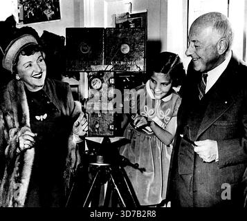 Kamera! Action! Cecil B. de Mille, der einzige amerikanische Regisseur, der die Stars an der Kinokasse überholt, Alice Faye, Filmschauspielerin, und DeMilles Enkelin Diane DeMille, 6, sieh dir eine der frühen Filmkameras an, auf einer Party, die DeMille gestern hier gab, um seine 40 Jahre im Showbusiness zu feiern. DeMille, jetzt 72, wird in diesem Herbst sein 70. Bild veröffentlichen, "die zehn Gebote". Dezember 1953. (Foto von AP Wirephoto). Stockfoto
