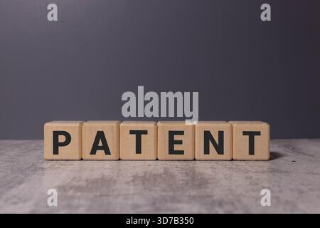 Lizenz. Wortpatent aus Holzwürfeln mit Buchstaben auf rosa Hintergrund, Großansicht Stockfoto