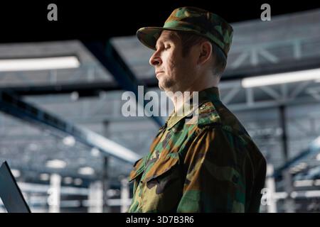 Experte für Informationstechnologie der Armee in Rechenzentren bei der Fehlersuche militärischer Computersysteme und Netzwerke mit Laptop. Soldat im Serverraum der Kommandozentrale mit Notebook-Gerät Stockfoto