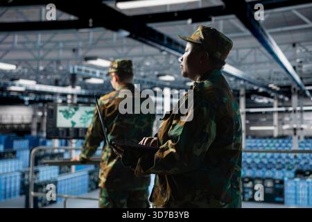 Militärtechniker im Kommandozentrum-Server-Hub mit Laptop zur Installation und Wartung von IT-Systemen. Administrator des afroamerikanischen Militärrechenzentrums für die Überwachung von Computernetzwerken und Informationssystemen, Kamera A Stockfoto