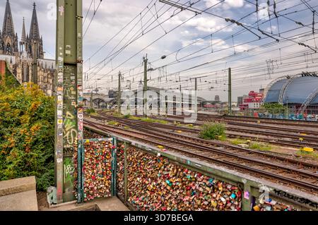 Bahngleise, die bei Sonnenaufgang bei bewölktem Himmel in Köln zur Hohenzollernbrücke und zum Dom führen Stockfoto