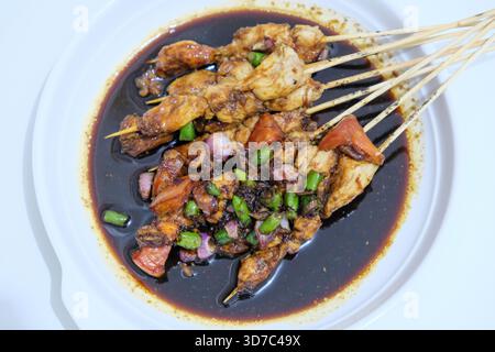 Indonesisches Essen, Hühnersatay oder Sate Ayam, serviert mit Sojasauce und Tomaten, Chilis und Schalotten Stockfoto