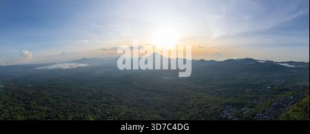 Atemberaubendes, weites Panorama einer Bergkette mit einem markanten Vulkangipfel, der über dem üppig grünen tropischen Wald ragt Stockfoto