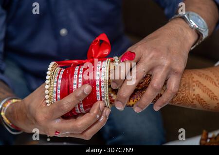 Bei einer Nahaufnahme werden die Hände der Braut mit Henna und die Hände des Bräutigams mit Armreif erfasst Stockfoto