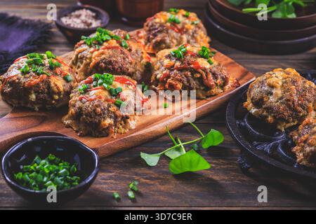 Im Ofen gebackene Fleischbällchen mit Fetakäse und frischen Kräutern auf Schneidebrett Stockfoto