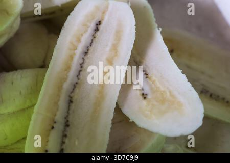 Nahaufnahme von frischer, roher Banane, in Hälften geschnitten, mit Innenseite von Zellstoff und schwarzem Samen. Tropische Früchte und gesunde Lebensmittelzutat für vegetarische oder vegane sterben Stockfoto