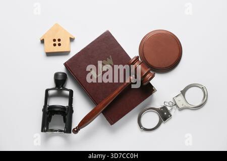 Richterlicher Hammer mit Gesetzbuch, Handschellen, Stempel und Hausfigur auf weißem Hintergrund Stockfoto