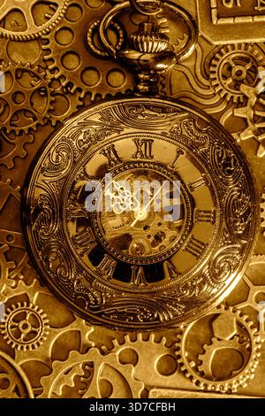 Goldene antike Taschenuhr mit Zahnrädern und Zahnrädern im Hintergrund. Vintage Industrial Steampunk Mode Accessoires. Stockfoto